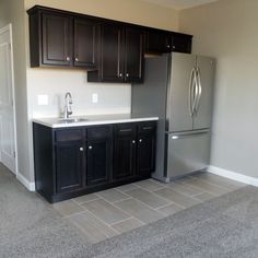 an empty kitchen with black cabinets and white counter tops is seen in this image from the doorway