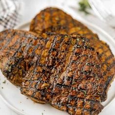 grilled steaks on a white plate with herbs