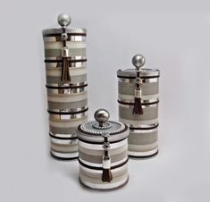 three different types of canisters with tassels and lids on each one