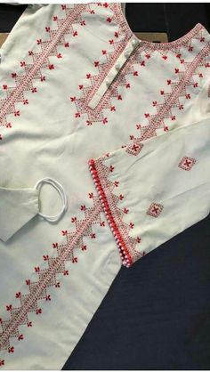 an embroidered white shirt with red trims on the collar and cuffs, sitting on a table