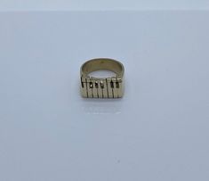 a gold ring with piano keys on the front and sides, sitting on a white surface