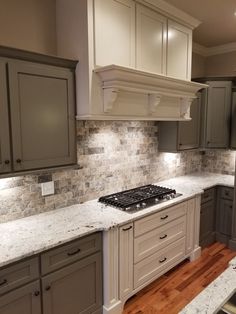 a kitchen with gray cabinets and white marble counter tops