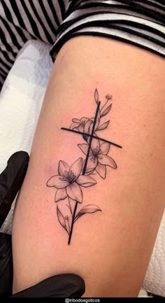 a woman's thigh with a cross and flowers tattoo on the side of her leg