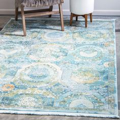 a blue rug with an ornate design on the floor in front of a white chair