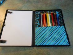 an open binder with colored pencils in it