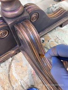 a person in blue gloves is working on a piece of furniture with wood and metal