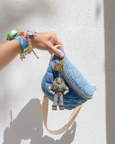 a hand holding a small blue purse with an animal decoration on the front and side