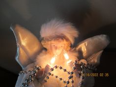 an angel holding a lit candle in its hands with beads on it's chest