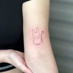 a small tattoo on the arm of a woman's left arm, with a rabbit holding an umbrella