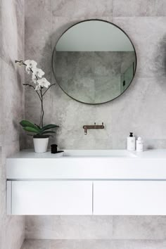 a white sink sitting under a round mirror