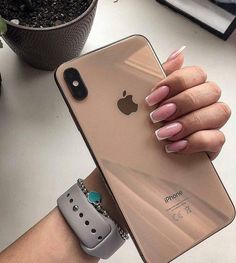 a woman's hand holding an iphone case on top of her wrist, next to a potted plant