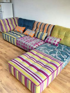 a multicolored sectional couch sitting on top of a hard wood floor