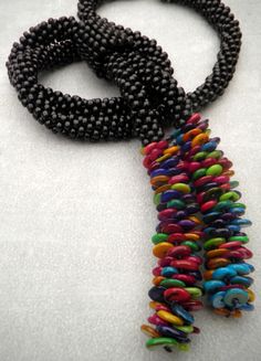 two necklaces that are on top of a white surface and one is black with multicolored beads