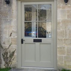 the front door to a building with a car in it's window and two lights on either side