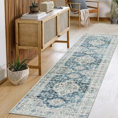 a living room area with a rug, chair and plant on the side of the floor