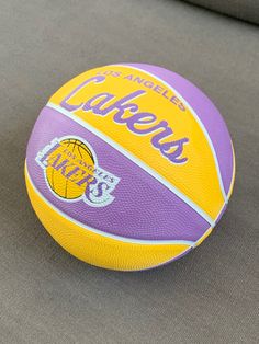 a purple and yellow basketball sitting on top of a gray couch next to a pillow