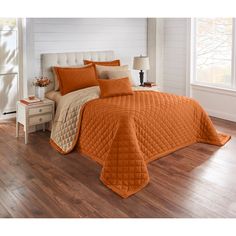 a bed with an orange comforter and pillows