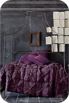 a bed with purple sheets and pillows in a room