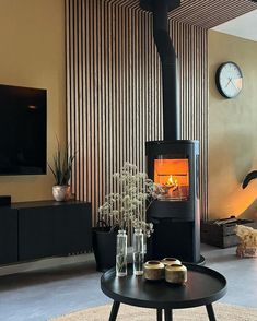 a living room with a fire place in the center and a clock on the wall