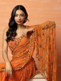 A two-piece Orange Mirror Prestitched Saree set from the Quench A Thirst collection – Zoraah 2022. This beautiful orange mirror blouse is paired with a matching orange mirror prestitched saree. The orange color with modal silk and soft net fabric enhances this saree set. There is an intricate floral hand-embroidery with cutdana beads, mirror, sequins, thread work details on the saree and the blouse. The sweetheart neck blouse has a back hook opening. Orange Net Saree, Orange Mirror Work Saree, Prestitched Saree, India Traditional Dress, Sweetheart Neck Blouse, Black Embroidered Blouse, Orange Lehenga, Mehendi Outfit