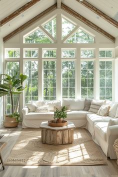 a living room filled with white furniture and large windows over the top of two couches