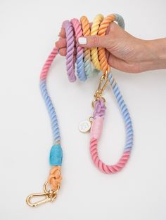 a person is holding several colorful bracelets on a white surface with a gold hook