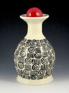 a black and white vase with a red ball in it