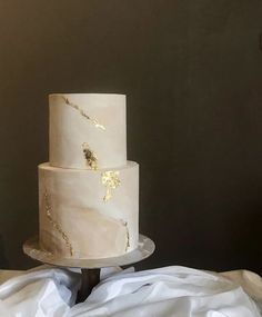 a three tiered cake with gold leaf decoration