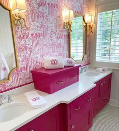 a bathroom with pink and gold decor on the walls, two sinks in front of a large mirror