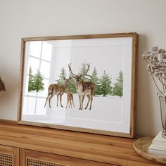 two deer standing next to each other on top of a wooden shelf in front of a window