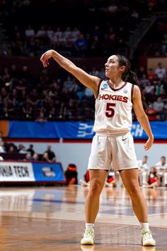 a female basketball player in action on the court with her hand up to the sky