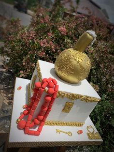 a cake made to look like a house with gold trimmings and decorations on top