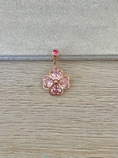 a pink diamond flower belly ring on a wooden surface