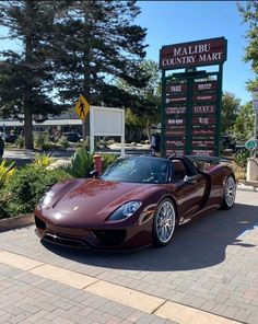 a red sports car parked in front of a sign