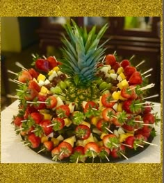 a pineapple surrounded by strawberries and other fruit on a platter with toothpicks