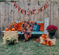 pumpkins and hay bales in front of a wooden fence with fall decorations on it