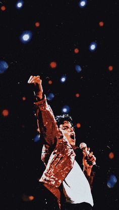 elvis presley performing on stage with his arms in the air and lights shining behind him