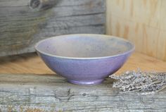 a purple bowl sitting on top of a wooden table next to a dried lavender plant