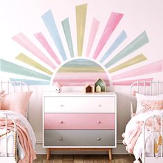 a bedroom with two beds and a dresser in front of a wall painted with colorful stripes