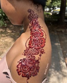 a woman with a tattoo on her back is looking down at the ground and trees