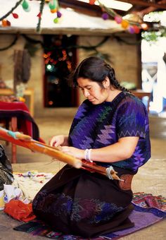 a woman is sitting on the floor working on something with a large wooden stick in her hand