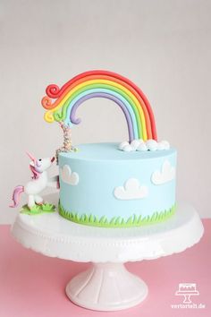 there is a cake with a rainbow decoration on the top and a unicorn figurine next to it