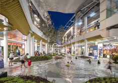 an indoor mall with people walking around and shopping on the first floor, at night