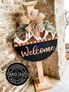 a welcome sign is displayed in front of a brick wall with a wreath on it