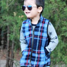 a young boy wearing sunglasses standing in front of trees