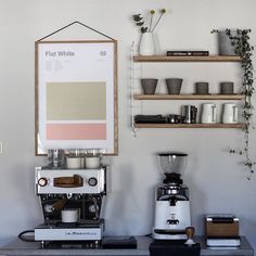 a coffee machine sitting on top of a table next to a shelf filled with cups