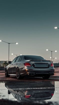 the rear end of a silver car parked in front of street lights