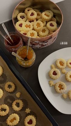 some cookies and jam are on a tray next to a bowl of jellys,