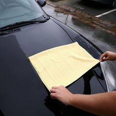 a person is cleaning the windshield of a car with a cloth on top of it