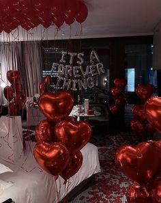 red balloons are floating in the air near a bed with white sheets and pillows on it